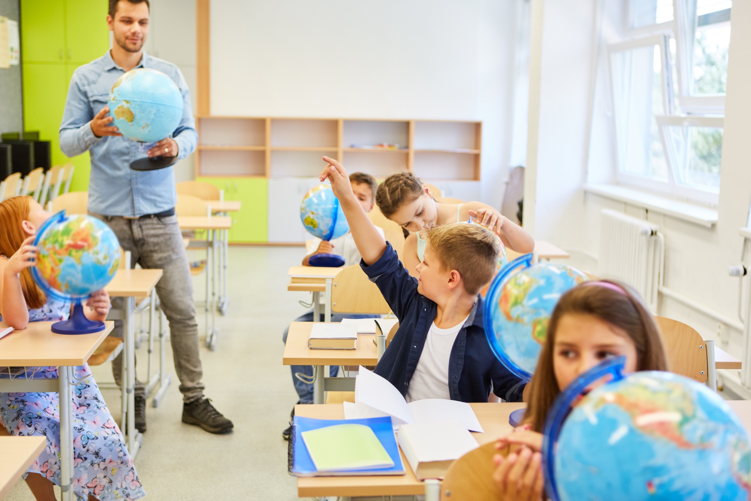 Elementary school teacher with a globe teaching class of children